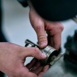Hands manipulate a metal device on a table.; mechanical pump seal