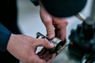Hands manipulate a metal device on a table.; mechanical pump seal