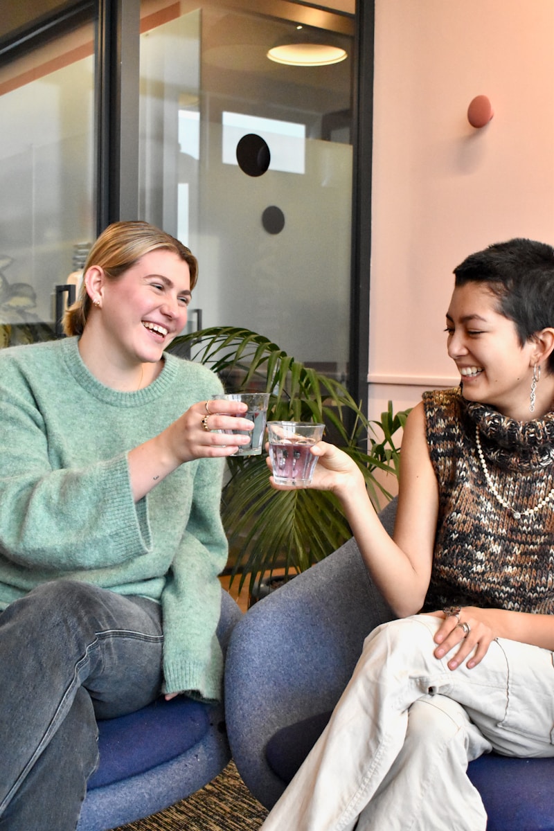 a couple of women sitting on top of a blue chair; bottleless water cooler office